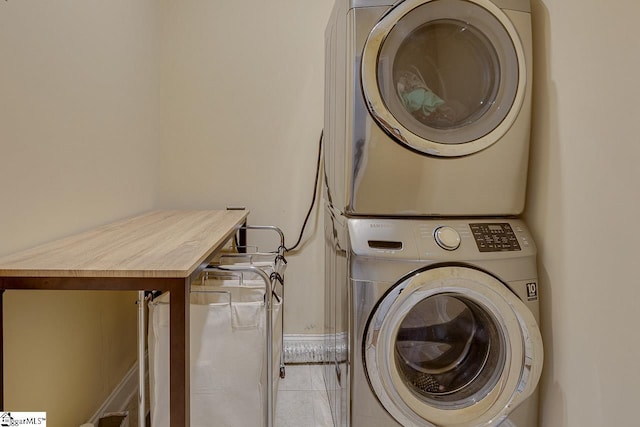 laundry area with stacked washer and clothes dryer and light tile patterned flooring