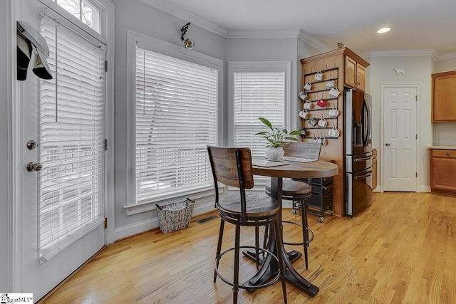 dining room with ornamental molding and light hardwood / wood-style floors