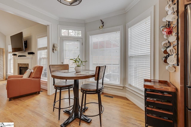 dining room featuring a healthy amount of sunlight, ornamental molding, and light hardwood / wood-style flooring