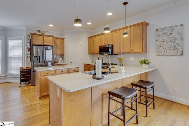 kitchen featuring a kitchen bar, decorative light fixtures, light hardwood / wood-style flooring, kitchen peninsula, and stainless steel appliances