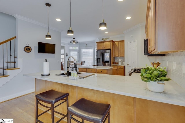 kitchen with stainless steel fridge, kitchen peninsula, sink, and backsplash