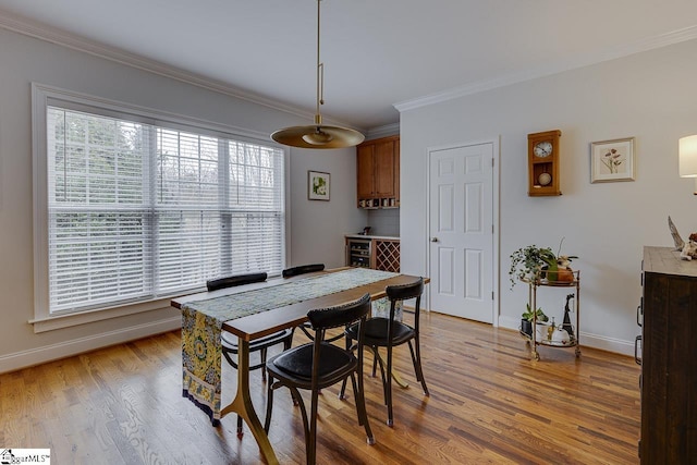 dining area with ornamental molding and light hardwood / wood-style floors