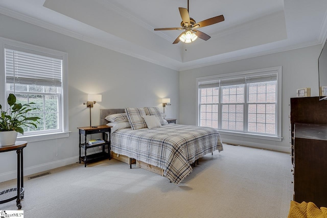 bedroom with crown molding, ceiling fan, a raised ceiling, and light carpet