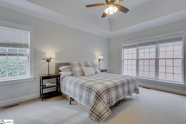 carpeted bedroom with a tray ceiling, ornamental molding, and ceiling fan