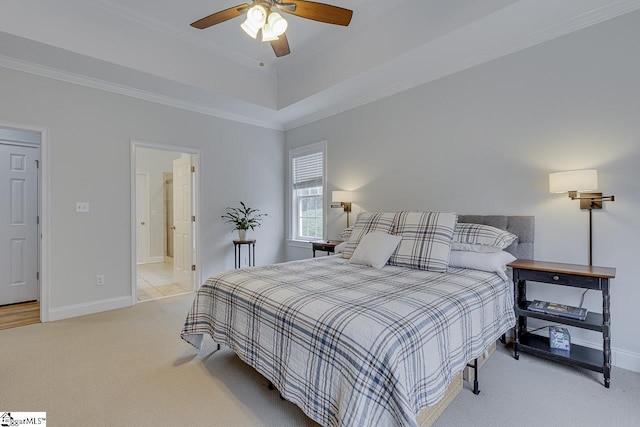 carpeted bedroom with a raised ceiling, crown molding, connected bathroom, and ceiling fan