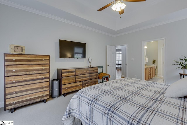 bedroom featuring ceiling fan, ensuite bathroom, ornamental molding, light carpet, and a raised ceiling