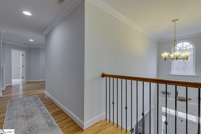 hall with an inviting chandelier, crown molding, and light wood-type flooring