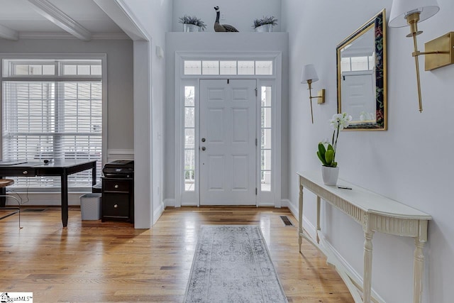 entrance foyer featuring crown molding, beam ceiling, and light hardwood / wood-style flooring