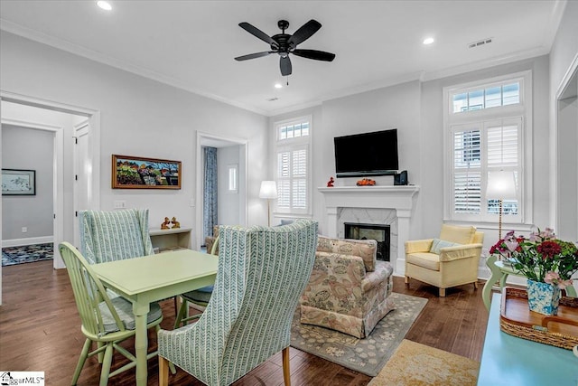 living room with a fireplace, crown molding, a wealth of natural light, and dark wood-type flooring