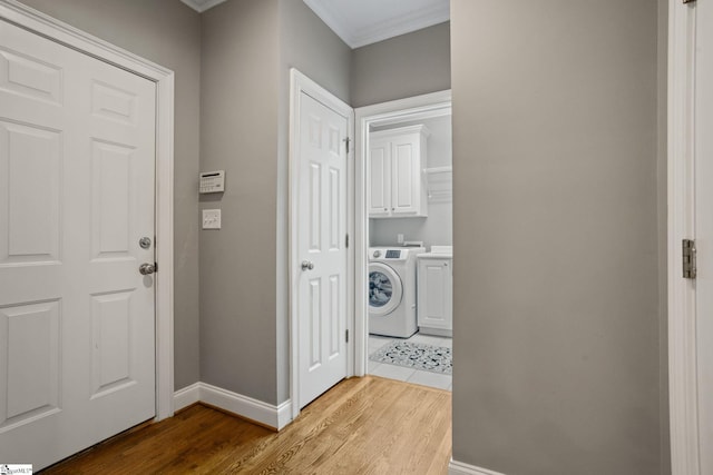 washroom featuring washer / clothes dryer, crown molding, light hardwood / wood-style flooring, and cabinets