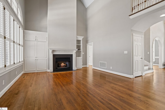 unfurnished living room with a towering ceiling and hardwood / wood-style flooring