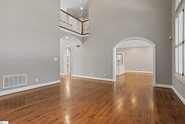 interior space with a towering ceiling, a healthy amount of sunlight, and dark hardwood / wood-style flooring