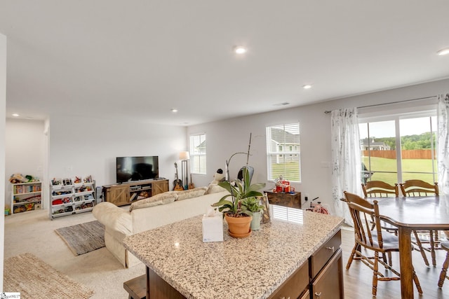 kitchen featuring light carpet, light stone countertops, and a center island