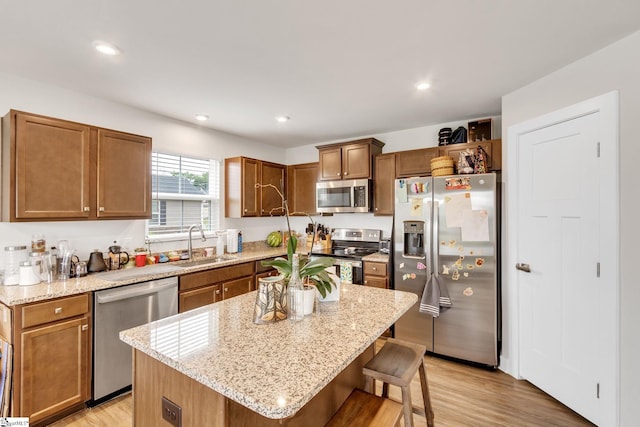 kitchen featuring sink, stainless steel appliances, a kitchen breakfast bar, light hardwood / wood-style floors, and a kitchen island