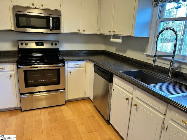 kitchen with white cabinetry, stainless steel appliances, sink, and light wood-type flooring