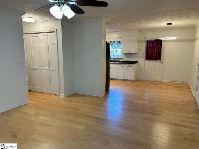 empty room with ornamental molding, ceiling fan, a textured ceiling, and light hardwood / wood-style floors