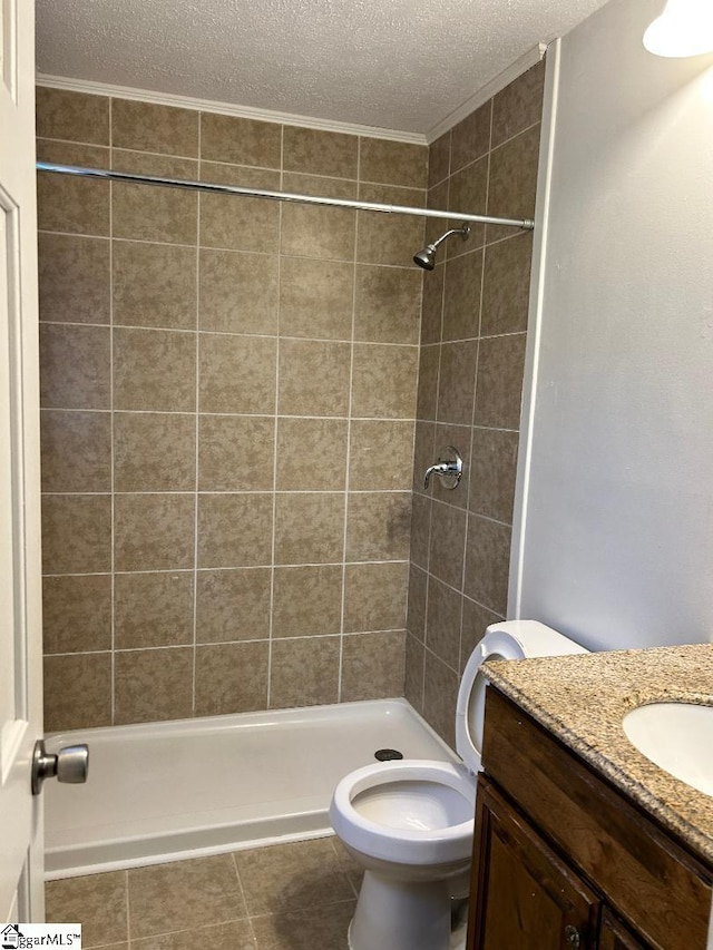 bathroom featuring vanity, tiled shower, a textured ceiling, and toilet