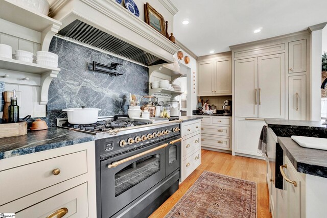 kitchen with decorative backsplash, double oven range, custom exhaust hood, and light wood-type flooring