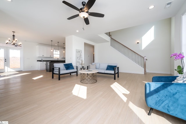 living room with french doors, sink, ceiling fan with notable chandelier, and light wood-type flooring