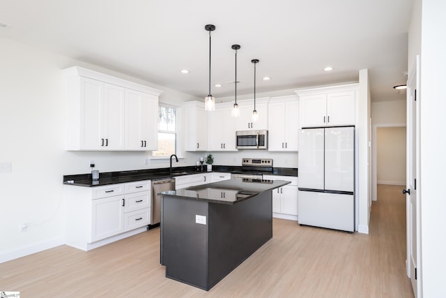 kitchen with pendant lighting, appliances with stainless steel finishes, a center island, light hardwood / wood-style floors, and white cabinets