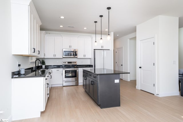 kitchen with pendant lighting, stainless steel appliances, a center island, and white cabinets