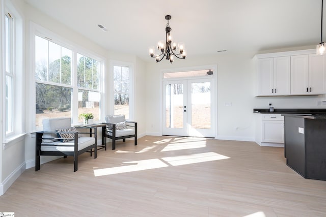 interior space with hanging light fixtures, white cabinetry, a healthy amount of sunlight, and french doors