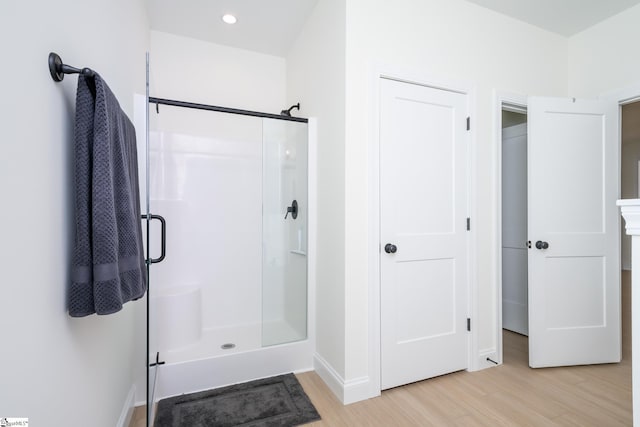 bathroom with wood-type flooring and a shower with shower door