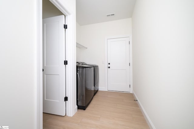 washroom featuring washing machine and clothes dryer and light hardwood / wood-style floors