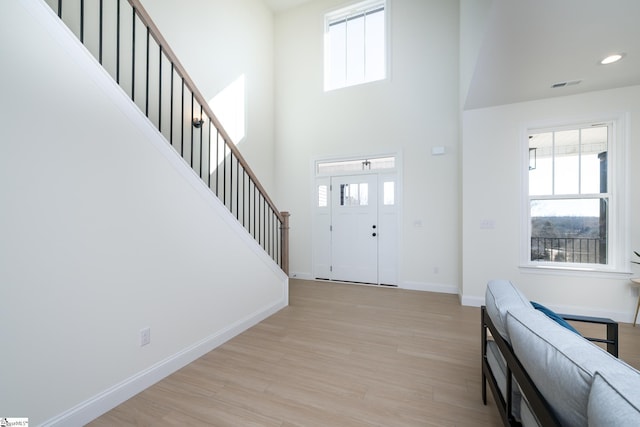 entryway with a towering ceiling and light wood-type flooring