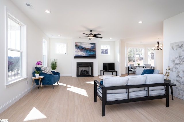 living room with ceiling fan with notable chandelier and light wood-type flooring