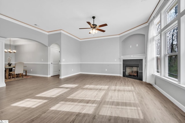 unfurnished living room with ornamental molding, ceiling fan with notable chandelier, a tile fireplace, and light wood-type flooring