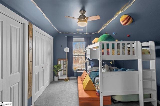 carpeted bedroom with multiple closets, ceiling fan, and vaulted ceiling