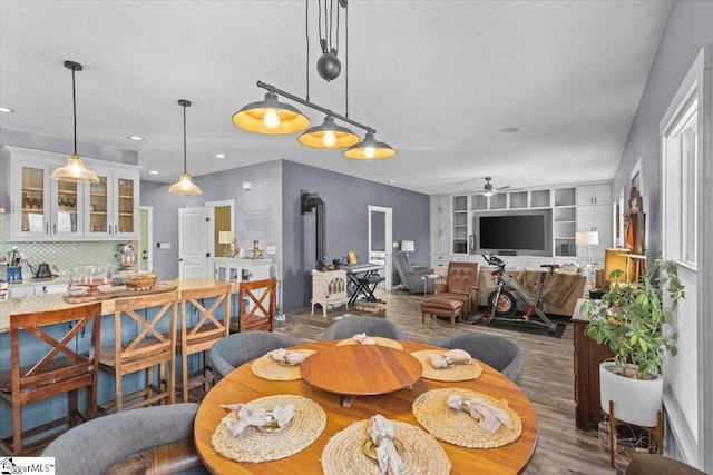 dining room featuring ceiling fan, a wood stove, dark hardwood / wood-style floors, and built in shelves