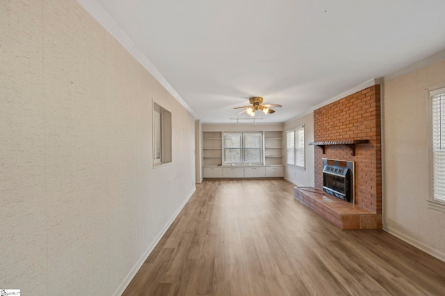 unfurnished living room with built in features, ceiling fan, hardwood / wood-style floors, a fireplace, and ornamental molding