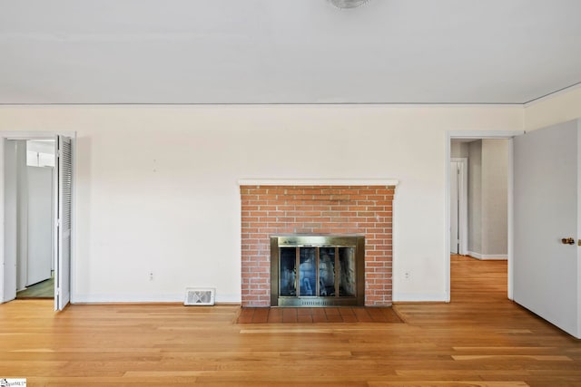 unfurnished living room featuring a brick fireplace and hardwood / wood-style flooring