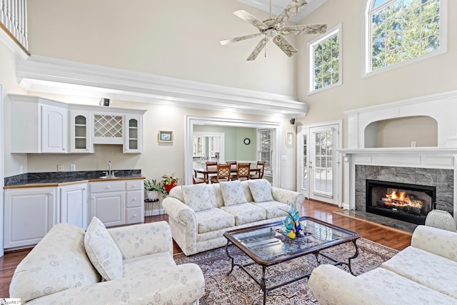 living room featuring indoor wet bar, ornamental molding, dark hardwood / wood-style flooring, ceiling fan, and a fireplace