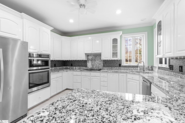 kitchen with sink, white cabinetry, backsplash, stainless steel appliances, and light stone countertops