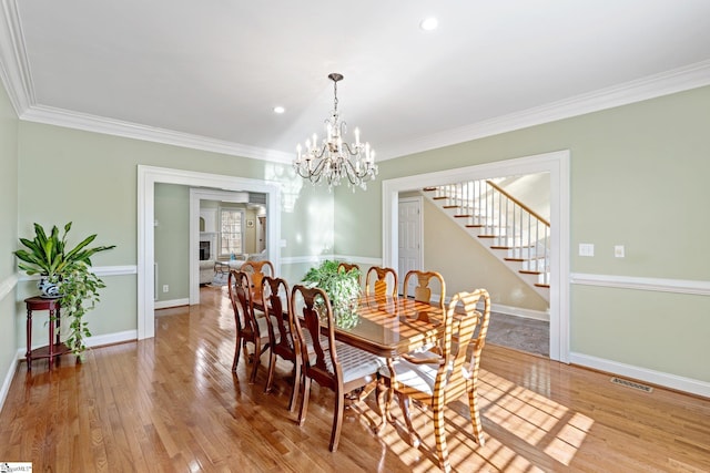 dining space featuring crown molding, a chandelier, and light wood-type flooring