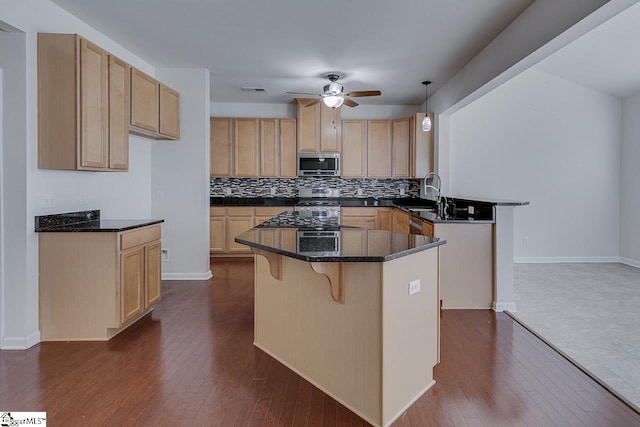 kitchen with stainless steel appliances, ceiling fan, hanging light fixtures, and dark hardwood / wood-style flooring