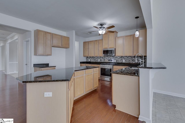 kitchen featuring hanging light fixtures, appliances with stainless steel finishes, sink, and dark stone countertops