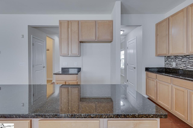 kitchen with tasteful backsplash, dark stone counters, and light brown cabinets