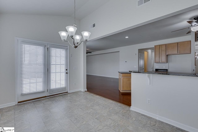 kitchen with ceiling fan with notable chandelier, a breakfast bar, decorative light fixtures, vaulted ceiling, and kitchen peninsula