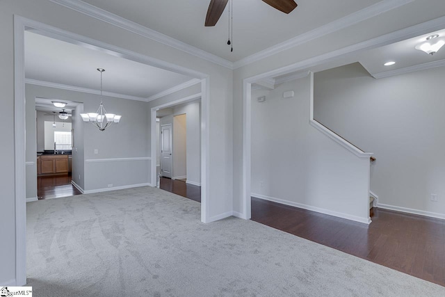 carpeted spare room featuring crown molding and ceiling fan with notable chandelier