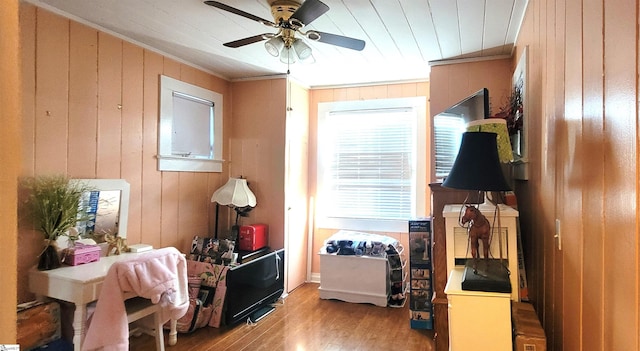 misc room with ceiling fan, ornamental molding, light hardwood / wood-style flooring, and wood walls