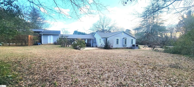 rear view of property featuring central AC unit, a yard, and a storage unit