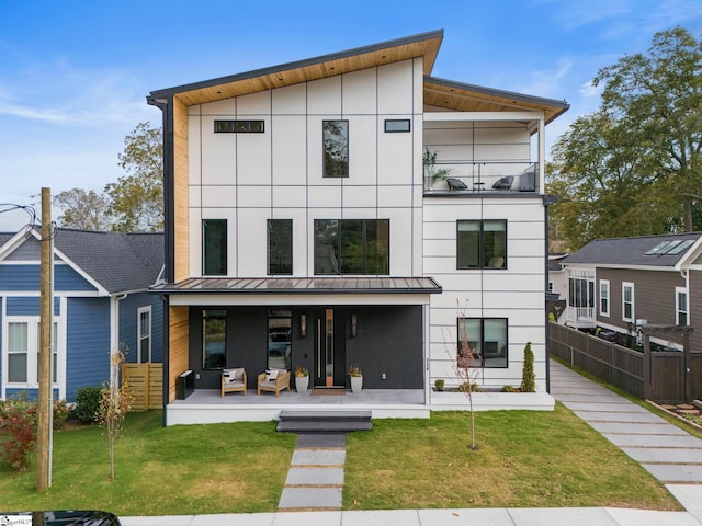 back of property featuring a yard, a patio area, and a balcony