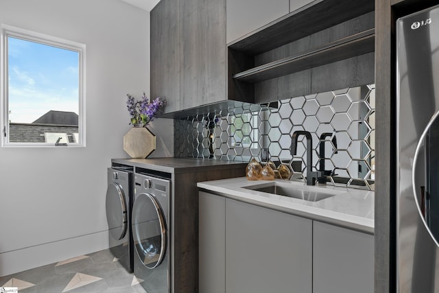 washroom with cabinets, washing machine and clothes dryer, and sink