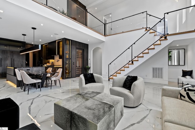 living room featuring wood walls, sink, and a high ceiling