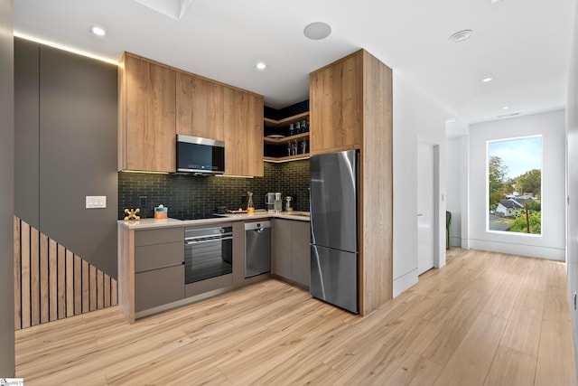 kitchen featuring stainless steel appliances, backsplash, and light wood-type flooring