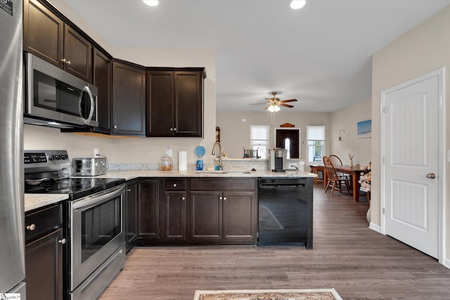 kitchen featuring dark brown cabinetry, sink, light wood-type flooring, appliances with stainless steel finishes, and kitchen peninsula